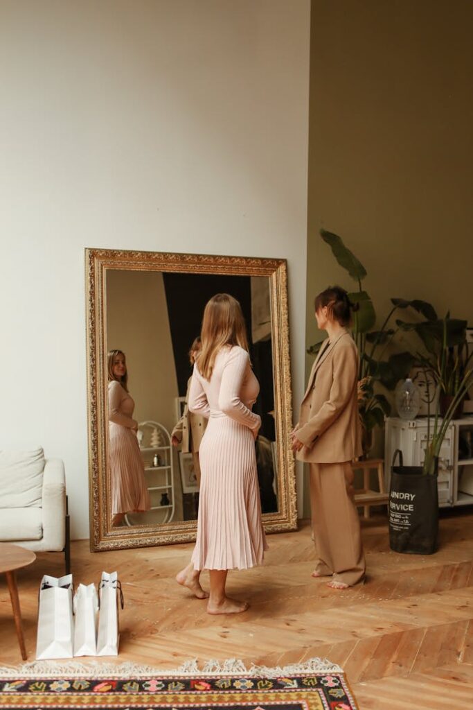 Two women shopping and trying on clothes indoors with a large ornate mirror.