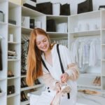 Young woman joyfully holding shoes in a modern boutique. Chic and stylish atmosphere.
